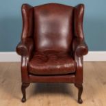 A contemporary marron leather upholstered wing back armchair