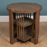 A Cotswold school limed oak circular occasional table with bookcase beneath