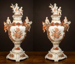 A pair of German porcelain urns on stands with the handles modelled as maidens