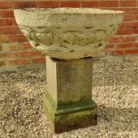 A cast reconstituted stone circular bowl shaped planter together with a stone plinth