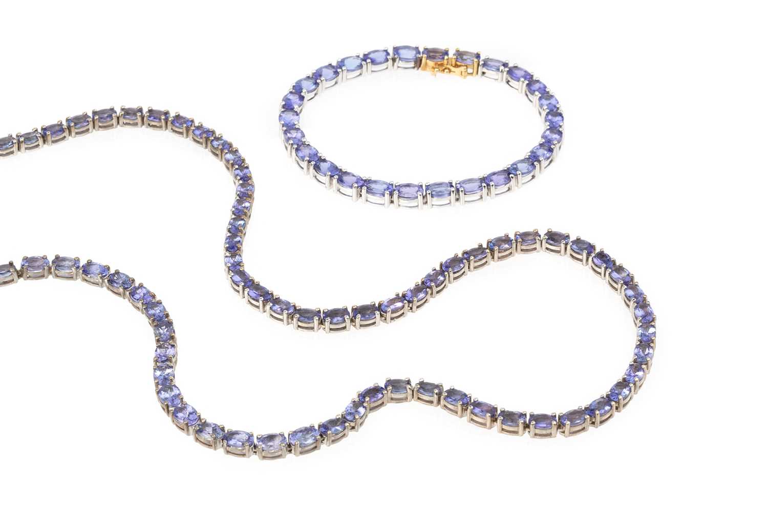 A collection of tanzanite jewellery, comprising a necklace and bracelet suite, each with a line of