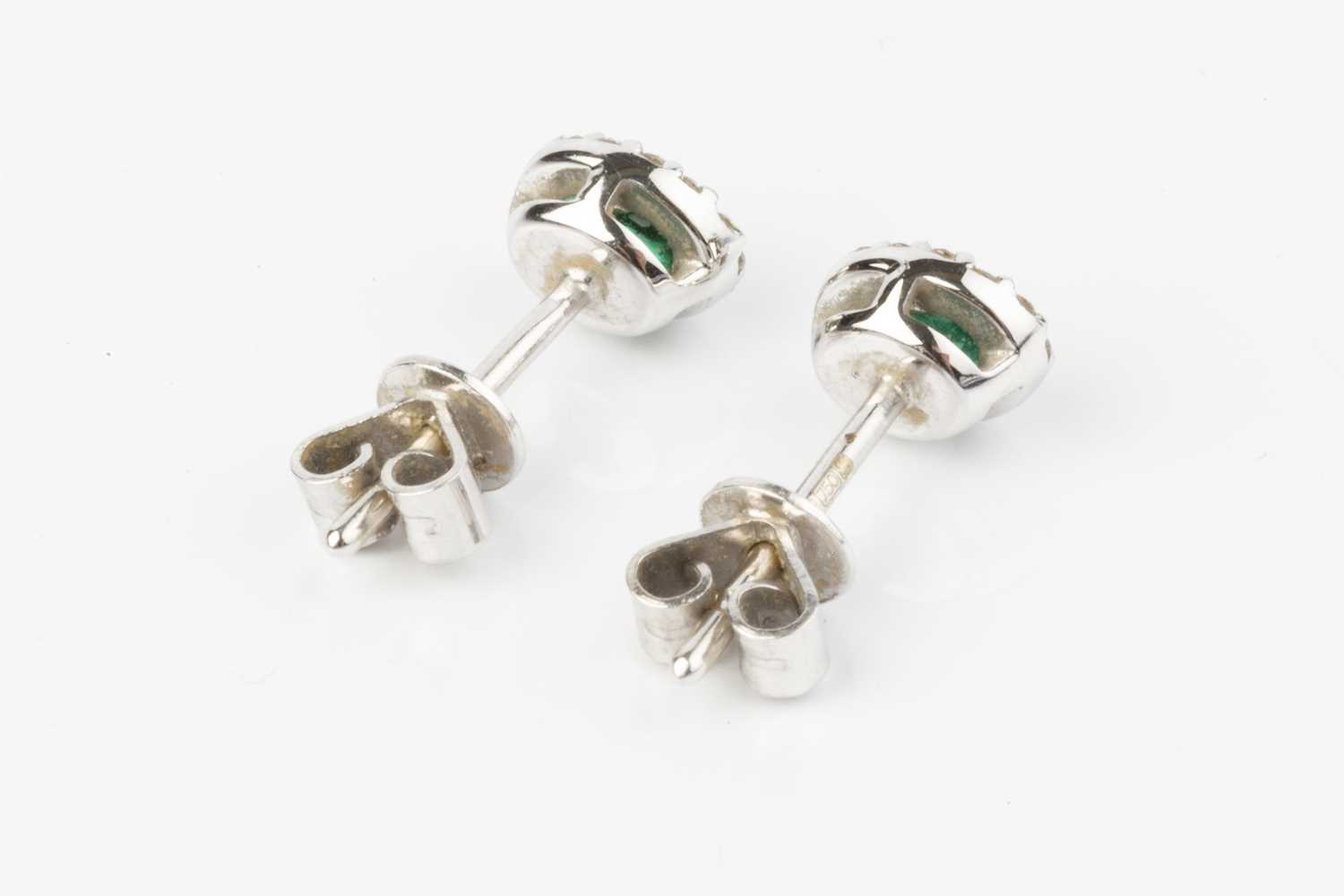 A pair of emerald and diamond cluster ear studs, each oval mixed-cut emerald bordered by round - Image 2 of 3