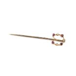 A ruby and diamond set stick pin, the openwork horseshoe-shaped panel accented with alternate old-
