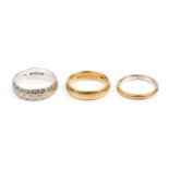 A 22ct gold wedding band, a 9ct white gold wedding band, with engraved decoration, and a two