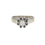 A diamond and sapphire cluster ring, the round brilliant-cut diamond claw set within a border of