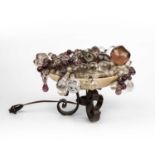 A late 19th century alabaster bowl with a scrolling wrought iron base filled with glass fruit and