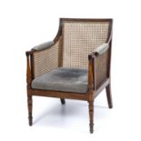 An early 19th century mahogany Bergere open armchair with a caned seat, back and sides, turned