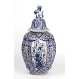 An antique Dutch Delft blue and white octagonal vase and cover with a lion finial and foliate