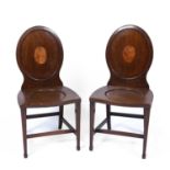 A pair of Georgian hall chairs with oval backs and square tapering legs terminating in spade feet,
