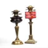 A victorian brass oil lamp with a faceted cranberry glass well and Corinthian column stem, 52cm