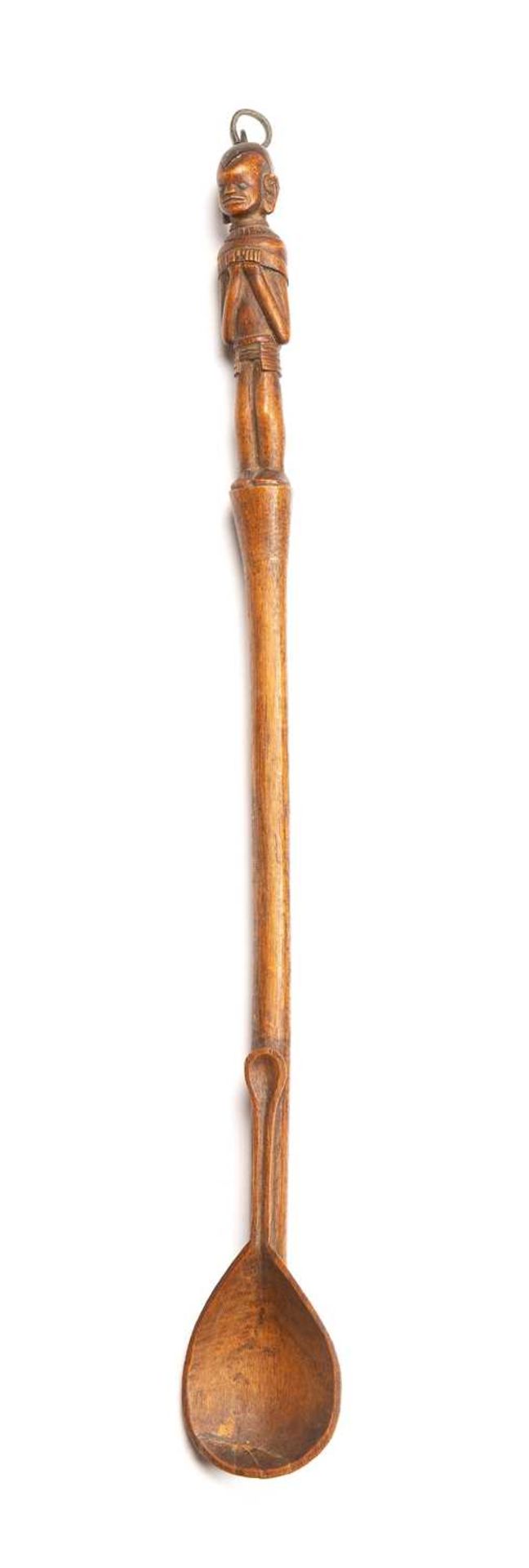 A Kamba Kenya carved wooden spoon with a female figure inlaid with metal eyes. 47cm in length.
