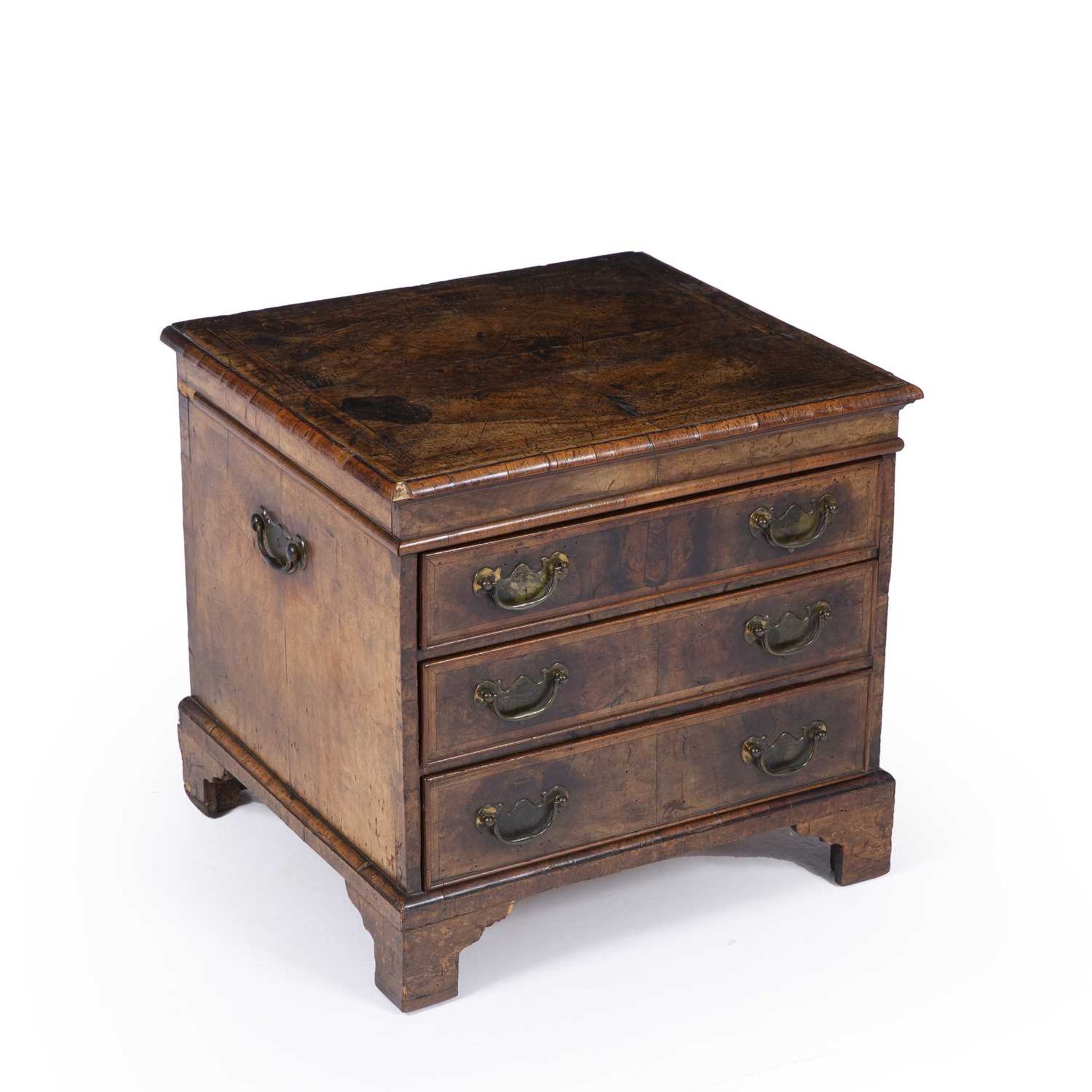 An antique and later walnut small chest of three drawers with brass carrying handles, brass ring