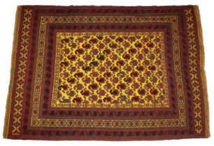 A 20th century middle eastern red and yellow ground woollen rug with a banded border and repeating