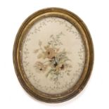 A late 18th century silk embroidered oval panel depicting flowers 36cm x 44cm mounted in a gilded