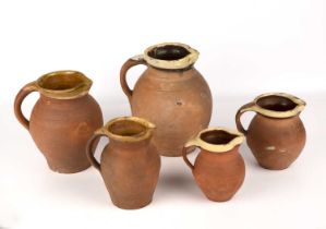 Five North Devon slipware jugs, the largest 22cm high