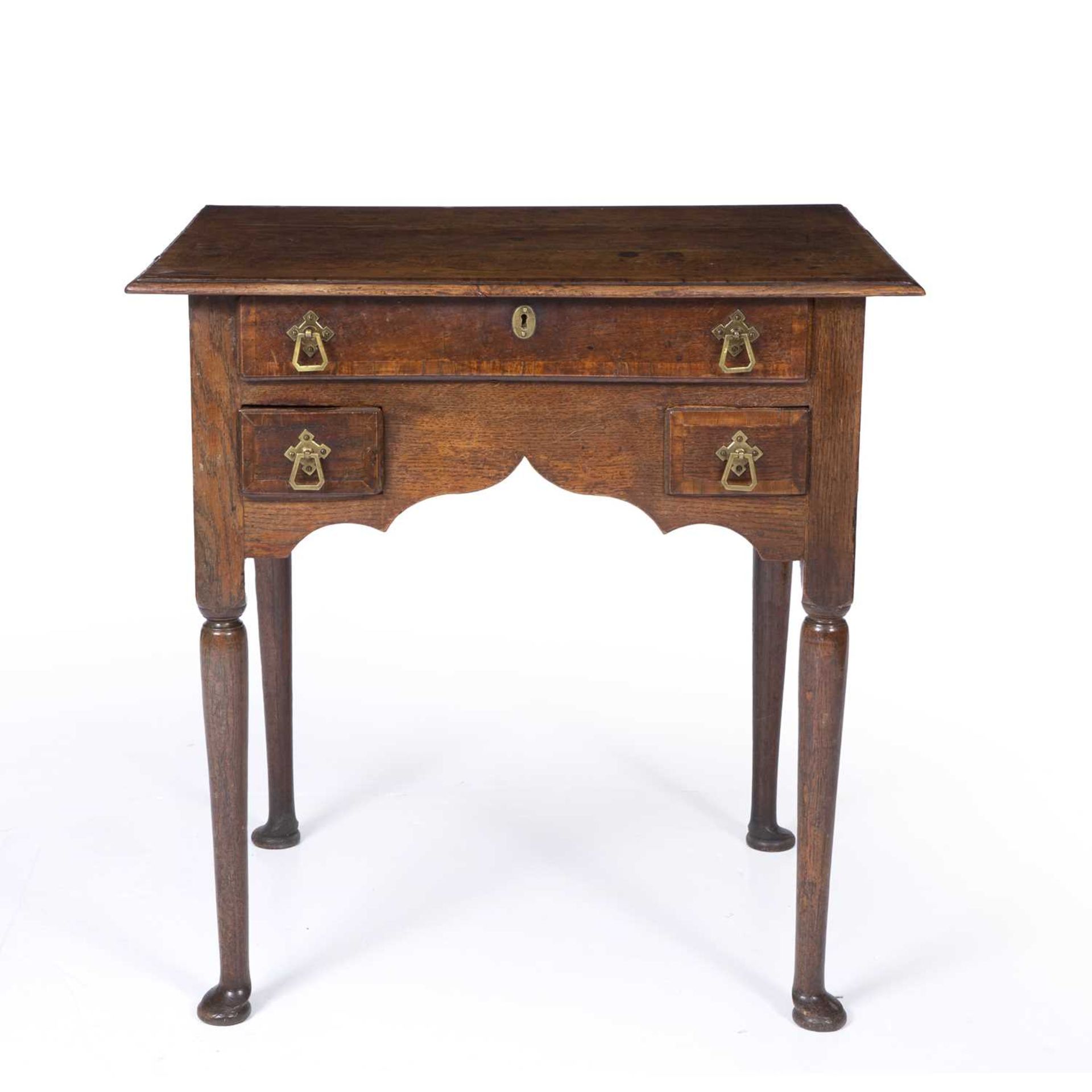 An 18th century oak low boy with three drawers and bras handles raised on turned legs and pad