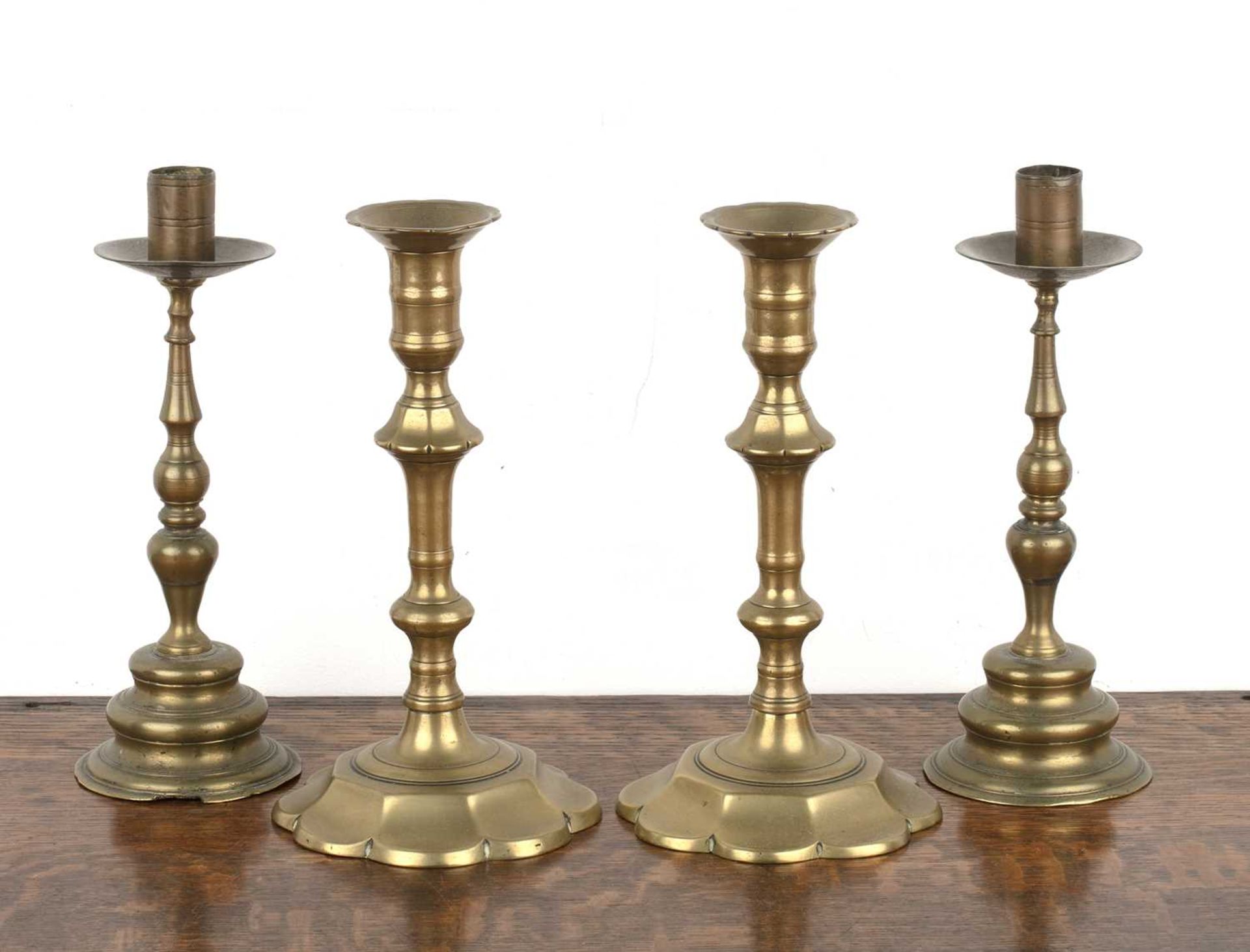 Two pairs of Continental brass candlesticks 18th Century and later, the smaller pair on shaped lotus