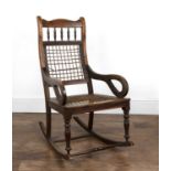 Rocking chair Dutch Colonial, possibly teak, with pear-shaped open arms, a gut webbed seat and back,