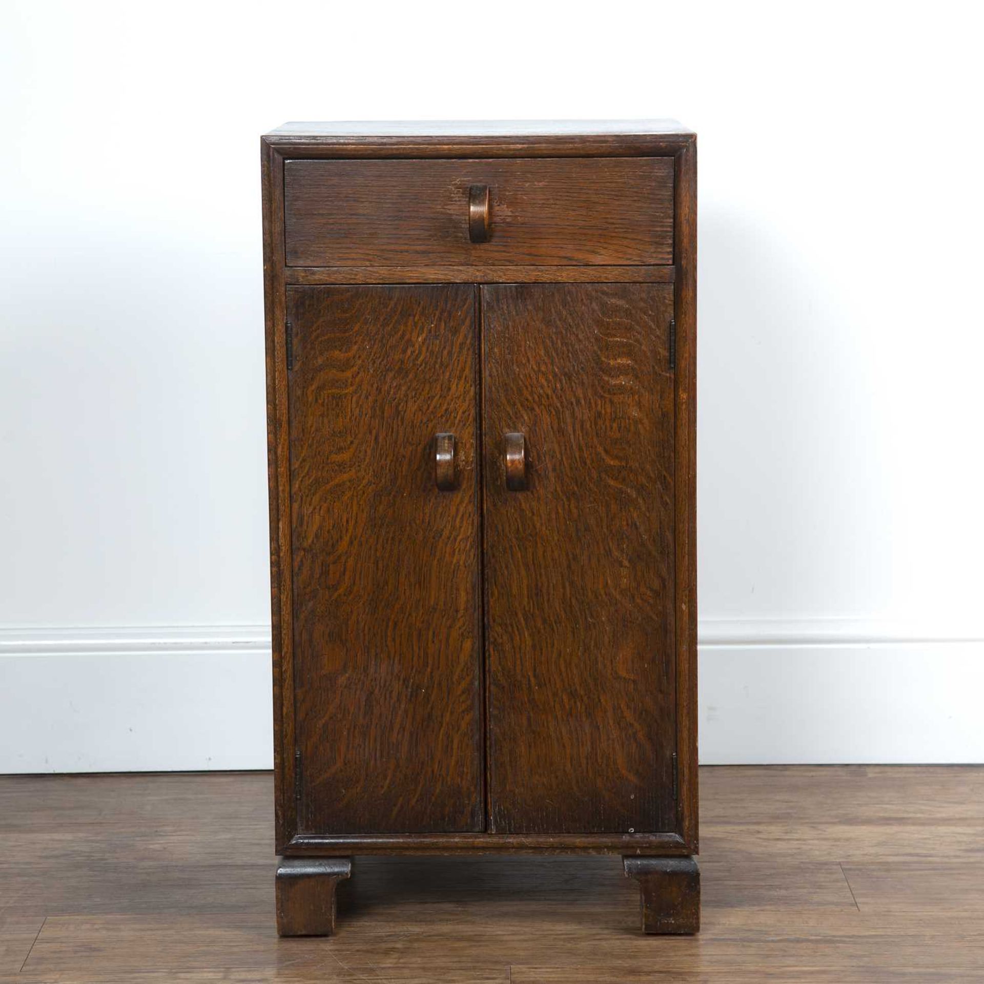 Herbert E. Gibbs dark oak side cupboard or bedside cupboard, with stylised handles, standing on