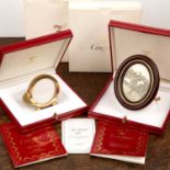 Must de Cartier Two boxed photo frames, one a circular brass example numbered '21033407' to the