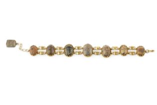 A scarab bracelet, designed as a series of slightly graduated scarabs in wirework edged settings,