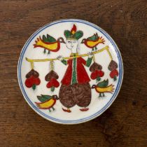 Kutahya pottery dish Turkey, painted with a figure holding a yoke with birds, 12.6cm diameter Hair