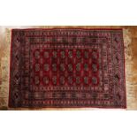 Red ground rug Pakistan, with a panel of elephant foot designs, 121cm x 172cm With some light wear.