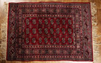 Red ground rug Pakistan, with a panel of elephant foot designs, 121cm x 172cm With some light wear.