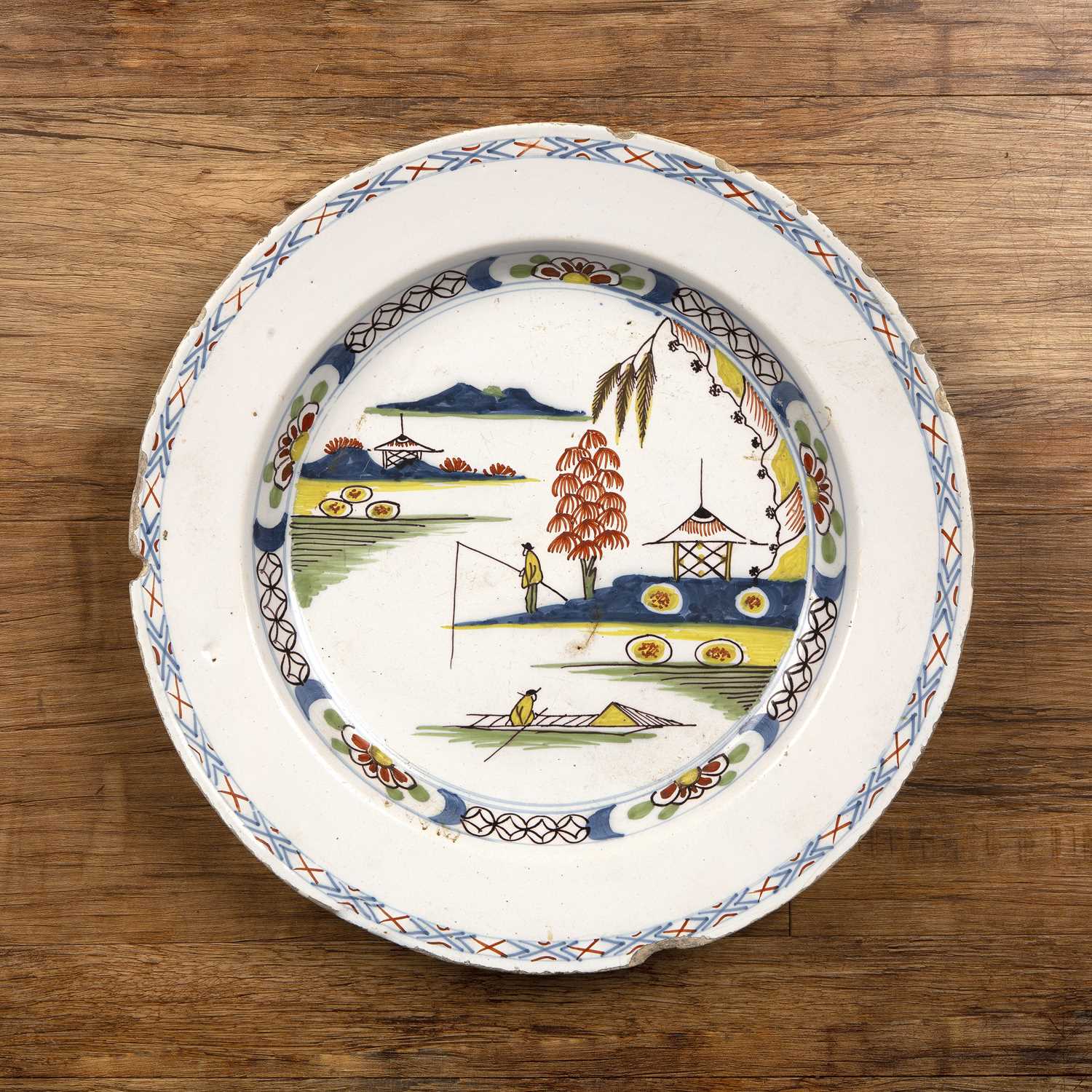 Polychrome Delftware charger English, circa 1780, painted with a Chinese landscape and fishermen,