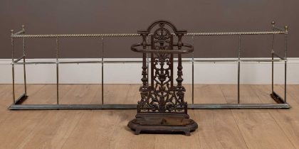 A cast iron umbrella stand and an antique brass fender