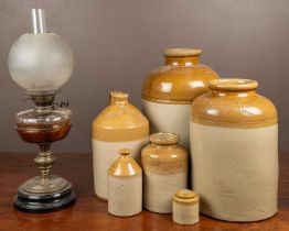 A group of stoneware jars and an old oil lamp