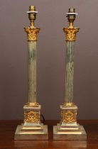 A pair of gilt metal and brass table lamps styled as Corinthian columns with gilt mounted decoration