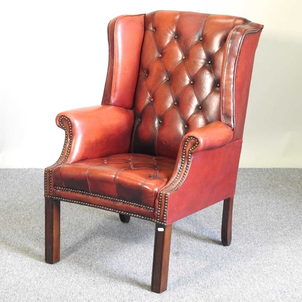 A red leather upholstered button back armchair