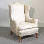 A 1920's cream upholstered wing armchair