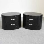 A pair of black oval bedside chests