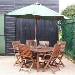 A teak garden table, chairs and parasol