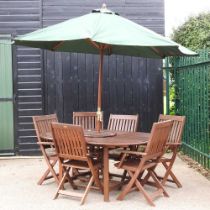 A teak garden table, chairs and parasol