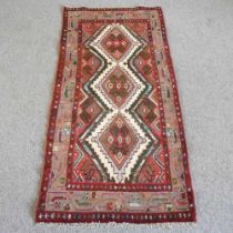 A Persian rug, with three central medallions, on a red ground, 160 x 80cm