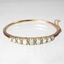 An unmarked opal hinged bangle, set with a single row of nine graduated opals, separated by