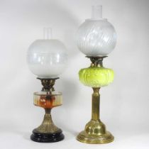 A brass oil lamp with an etched glass shade, together with another with a green glass reservoir,