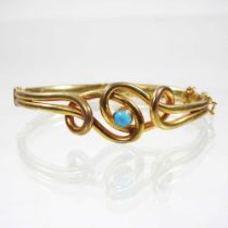 An early 20th century gold and set turquoise hinged bangle, of interlaced design, marks rubbed, 7.