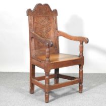 A 17th century style oak wainscot chair, 20th century, decorated with scrolling foliate designs,