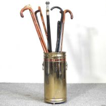 A brass stick stand, 46cm high, containing a collection of walking sticks
