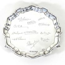 An early 20th century silver salver, of circular shape, with a piecrust border, with signatures