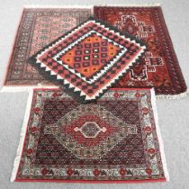 A Persian rug, with a hooked central medallion, on a red ground, 136 x 79cm, together with three