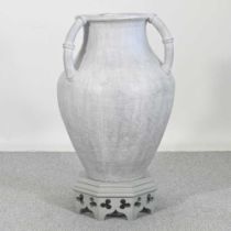 A large glazed terracotta urn, on a wooden stand, 90cm high overall approx 50cm wide One handle