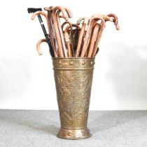 A brass stick stand, 84cm high, containing a collection of walking sticks
