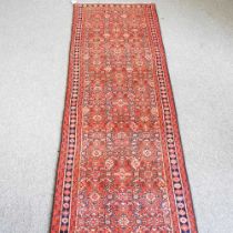 A Persian runner, with all over designs, on a red ground, 408 x 84cm