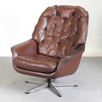 A 1960's Danish brown leather swivel lounge armchair, with a buttoned back, on a metal base, by HW