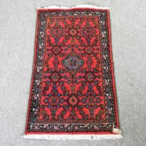 A Persian woollen rug, on a red ground, 122 x 70cm